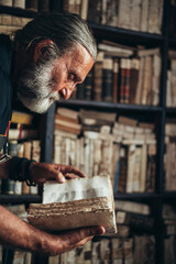 Senior man hands holding an old book in a library