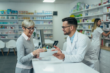 Senior woman customer buying medications at drugstore while talking with a male pharmacist