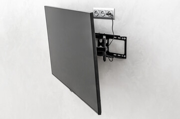 Modern tv hanging on the wall. Tv mounted with special fasteners in the room. - 471787307