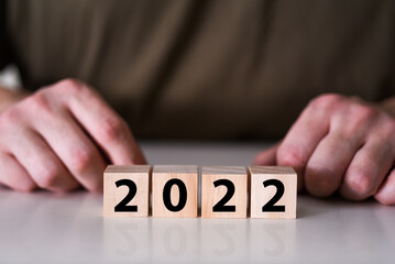 A businessman holds a wooden cubic block, for the year 2022.
