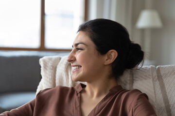 Head shot joyful attractive millennial indian ethnicity woman resting in comfortable armchair,...