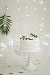 A cake on a high stand and decorations of green twigs 3408.