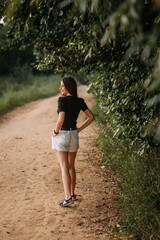 A young beauty walks under the rays of the summer sun in the meadows