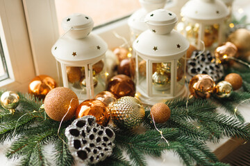 Close up of holidays location with gold balls toys and white candlesticks on a window