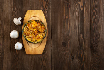 Homemade julienne with cheese and mushrooms . A hot dish with baked cheese crust on a wooden  table.