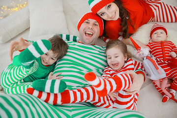 christmas pajama striped party family with kids, new year costumes, fun at home in bed