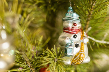 Close up of holidays location with snowman toy and garlands on green Christmas tree