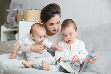 mom plays and reads books with two  little kids. mother spends time with two child sons at home.  place for text. copy space. family time at home
