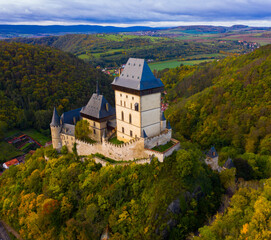 Obraz premium Picturesque autumn landscape with imposing medieval Karlstejn Castle on hilltop above village of same name, Czech Republic
