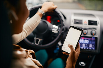 Close-up of woman text messaging on mobile phone while driving car.