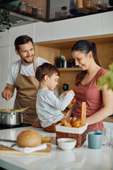 Happy family enjoys while preparing meal in the kitchen.