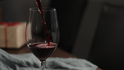 pour red wine into wineglass with gift box on background