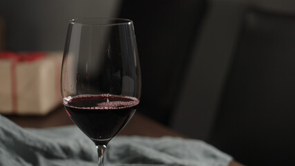 pour red wine into wineglass with gift box on background