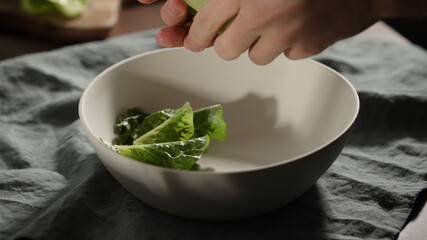 man put baby romaine leaves in white bowl