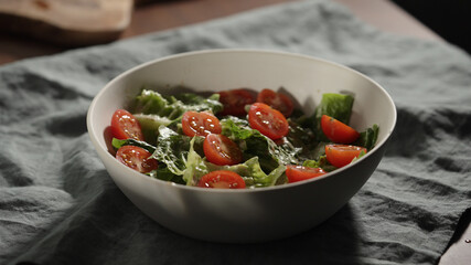 cherry tomatoes to romaine leaves in white bowl