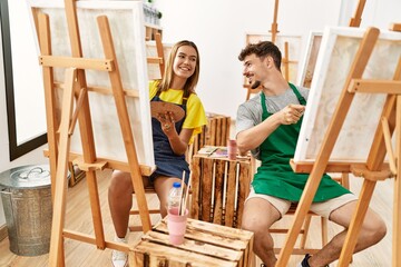 Young hispanic artist couple smiling happy drawing at art studio.