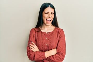 Young hispanic woman wearing casual clothes winking looking at the camera with sexy expression,...