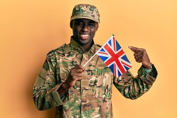 Young african american man wearing army uniform holding united kingdom flag smiling happy pointing with hand and finger
