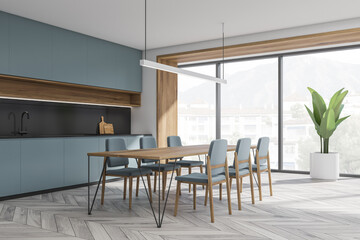 Corner of minimalist blue and grey kitchen with dining table
