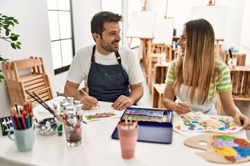 Fototapeta premium Two students smiling happy painting sitting on the table at art school.