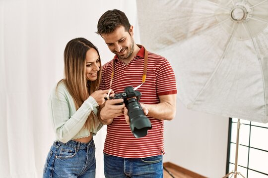 Professional photographer showing camera photos to model at photography studio.