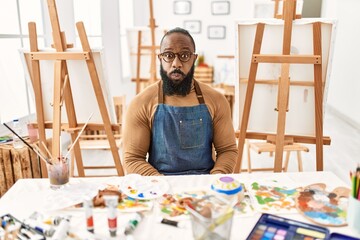 African american artist man at art studio puffing cheeks with funny face. mouth inflated with air, crazy expression.