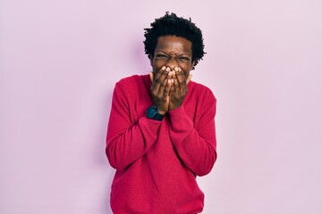 Young african american man wearing casual clothes laughing and embarrassed giggle covering mouth...
