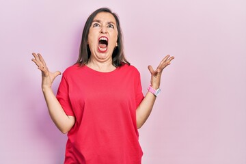 Middle age hispanic woman wearing casual clothes crazy and mad shouting and yelling with aggressive expression and arms raised. frustration concept.