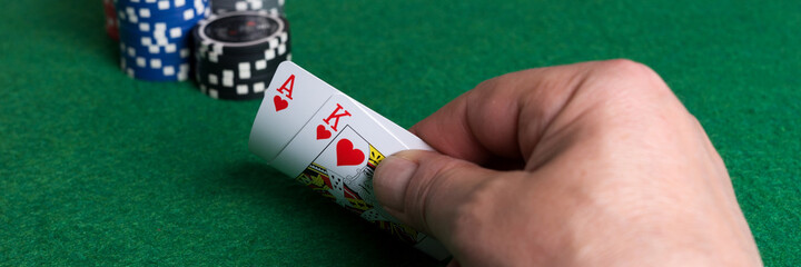 Ace of hearts and red heart king in the hand with poker chips in the background. Panoramic image