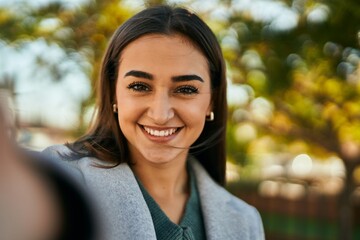 Young hispanic girl smiling happy making selfie by the camera at the city.