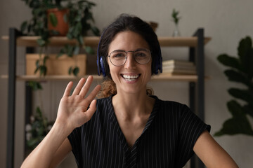 Headshot screen portrait of friendly young latin lady in glasses headset teacher blogger look at...