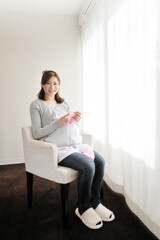 Obraz na płótnie Canvas 窓辺で編み物をする妊婦