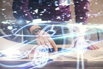 Double exposure of man's hands holding and using a digital device and automobile theme hologram drawing. Technology concept.