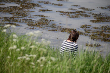 Frau sitzt traurig alleine am Ufer