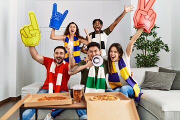 Obraz premium Group of young friends watching and supporting soccer match at home.