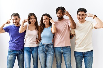 Obraz premium Group of young people standing together over isolated background smiling pointing to head with one finger, great idea or thought, good memory
