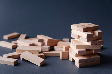 Jenga tower made of wooden blocks on gray-blue background, space for text