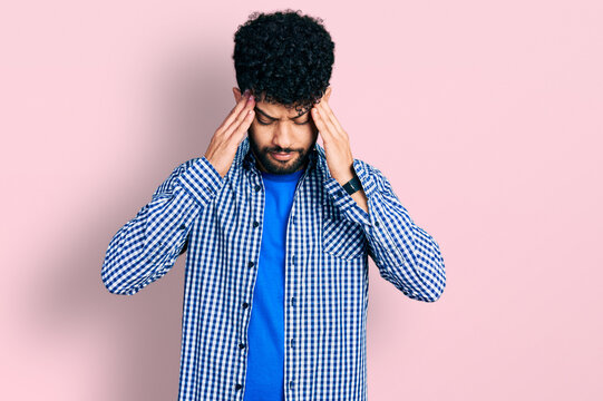 Young arab man with beard wearing casual shirt with hand on head, headache because stress. suffering migraine.