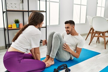 Young hispanic couple doing abs exercise at home