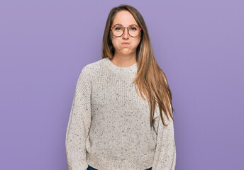 Obraz premium Young blonde woman wearing casual sweater and glasses puffing cheeks with funny face. mouth inflated with air, crazy expression.