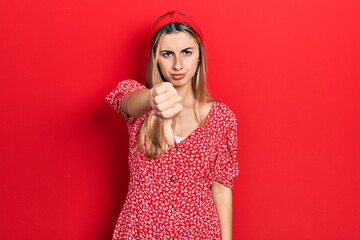 Beautiful hispanic woman wearing summer dress looking unhappy and angry showing rejection and negative with thumbs down gesture. bad expression.