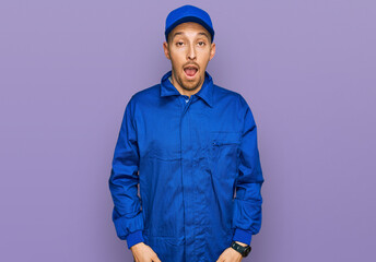 Bald man with beard wearing builder jumpsuit uniform afraid and shocked with surprise and amazed expression, fear and excited face.