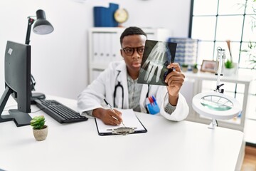 Young african man working as doctor looking at hand xray at medical clinic