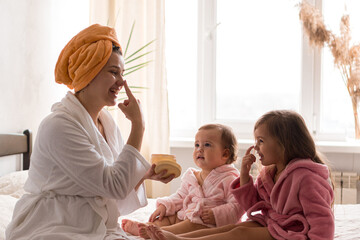 Young mother two daughters in curlers bathrobes. happy smiling family skin care concept. Mom...