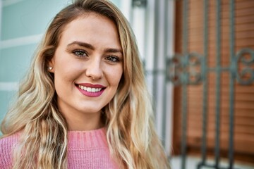 Young blonde woman smiling at the city