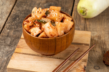 Korean recipe pickled radish cubes in a wooden bowl on a wooden board.