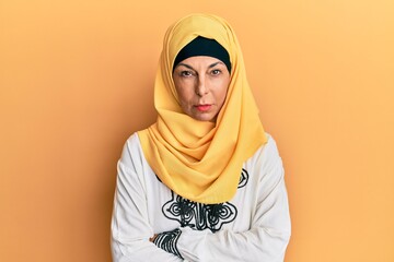 Middle age hispanic woman wearing traditional islamic hijab scarf skeptic and nervous, disapproving expression on face with crossed arms. negative person.