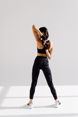 Back view portrait of a young woman stretching hands on a white background