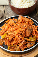 Korean salad of fish and carrots with onions, garlic. Fish he in Korean. Wooden background.
