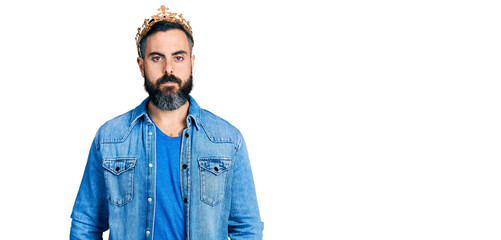 Hispanic man with beard wearing king crown with serious expression on face. simple and natural looking at the camera.